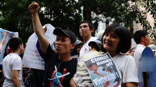Bà Trần Thị Nga ôm con trai và một tấm áp phích chống Trung Quốc, 8/7/2012, khi tham gia một cuộc biểu tình chống Trung Quốc ở Hà Nội.