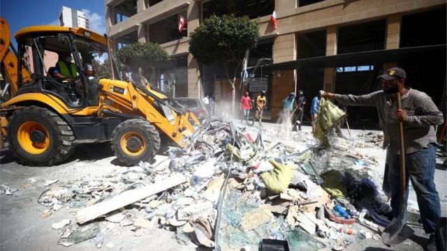 لبنانيون يزيلون حطاما ناتجا عن الانفجار من أحد شوارع بيروت