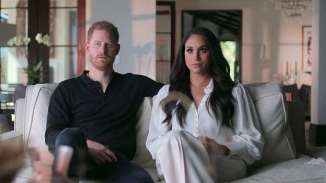 Harry e Meghan sentados no sofá