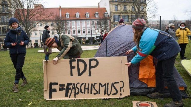 Demonstranten mit Plakaten greifen die FDP an.