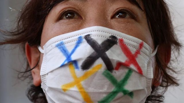Seorang perempuan mengenakan masker dengan logo Olimpiade