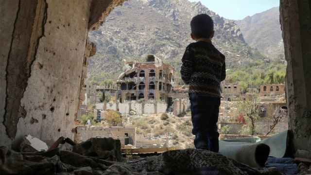 طفل يمني ينظر إلى أطلال مبان مدمرة