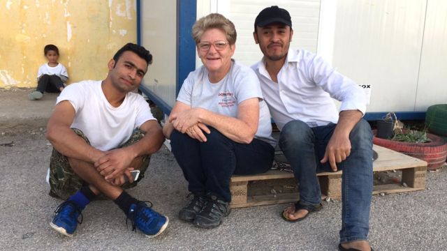 Lisa Campbell sentada junto a residente del campo de Oinofyta