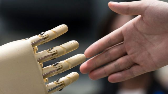 Una mano de robot y una mano humana a punto de estrecharse