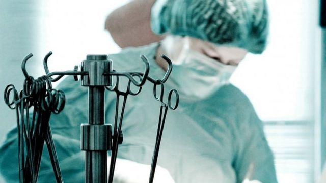 Хірург робить операцію на серці, поруч висять скальпелі
