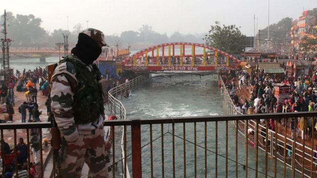 Indian security personnel stands guard on the banks of the River Ganges during Makar Sankranti, a day considered to be great religious significance in Hindu mythology, on the first day of the religious Kumbh Mela festival in Haridwar on 14 January 2021