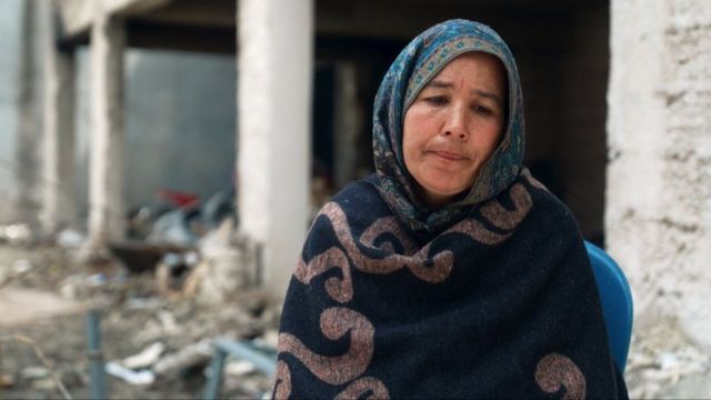 Zahra Charizada sits near to a damaged building