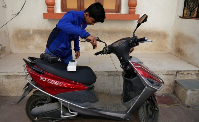 Индийский мальчик заряжает электромопед