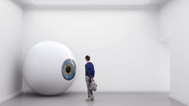 A woman observes a reproduction of a giant eye