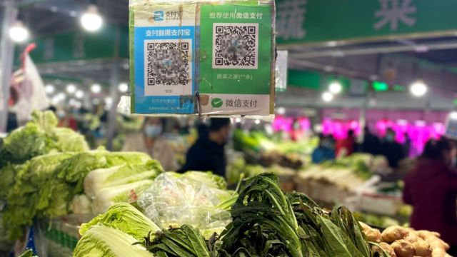 Los códigos de pago de WeChat Pay y Alipay colgados en un puesto en un mercado de verduras en Pekín, China.