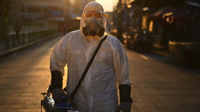 Trabajador desinfectando una calle en San Salvador.