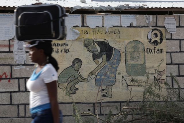 إمرأة تمر أمام مخيم للنازحين من زلزال 2010، على مشارف بورت أو برنس، هايتي، 13 فبراير/شباط 2018