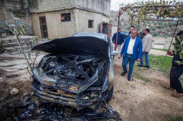 Palestinos assistem a um de seus veículos supostamente incendiado por colonos israelenses na Cisjordânia.