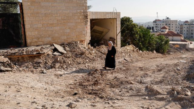 Una mujer palestina camina cerca de su casa destruida