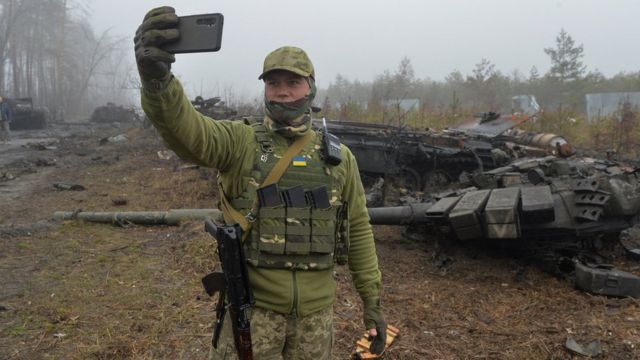 Ukrainian military is photographed against the background of a broken Russian tank