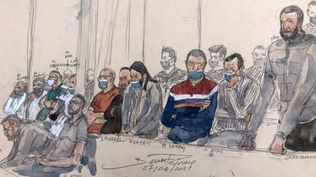 صلاح عبد السلام (إلى اليمين) يقف بجانب المدعى عليهم الثلاثة عشر الآخرين أمام محكمة جنايات باريس أثناء المحاكمة المتعلقة بهجمات نوفمبر/تشرين الثاني 2015 يوم 27 يونيو/حزيران.