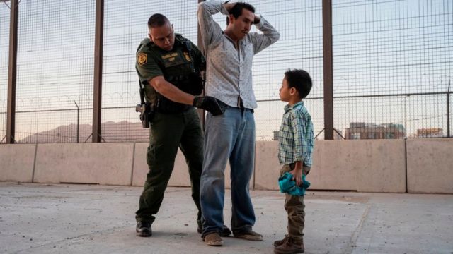 Un agente migratorio detiene a un hombre delante de un menor