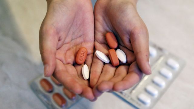 Paciente mostrando en sus manos las pastillas para el tratamiento contra el VIH
