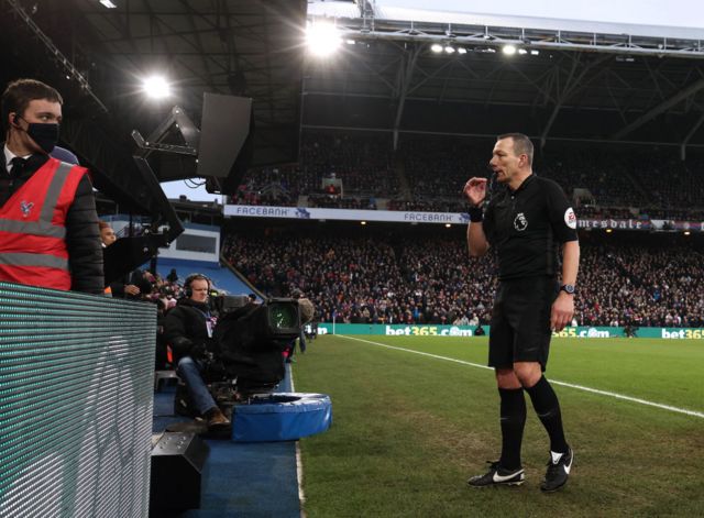 Referee Kevin Friend checks the pitch side monitor