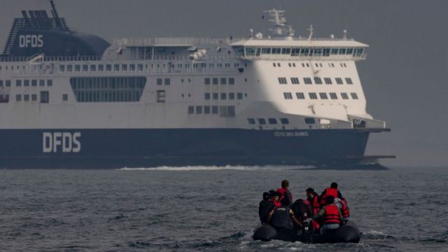 Una embarcación llena de inmigrantes en el canal de La Mancha junto a un ferry.