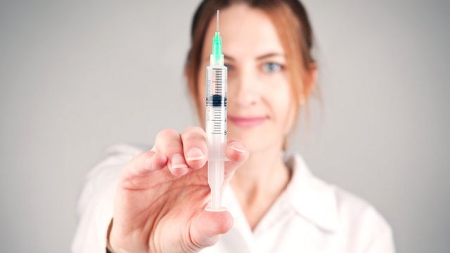 Mulher segurando agulha de vacina