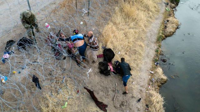 Люди по обе стороны забора на границе США и Мексики