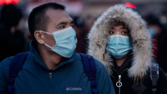 Chinese citizens wearing protective masks board trains in Beijing, 21 January 2020
