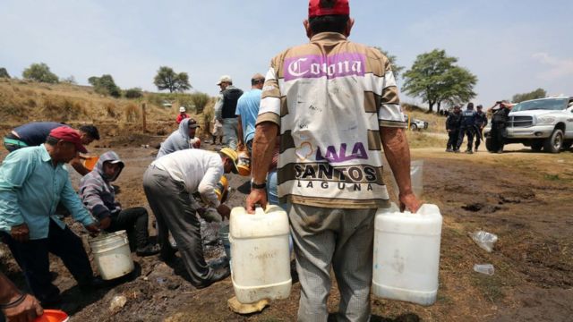 Residentes de Puebla recogen combustible de una fuga, con autorización de Pemex.