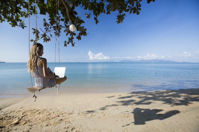 donna sulla spiaggia con il computer portatile