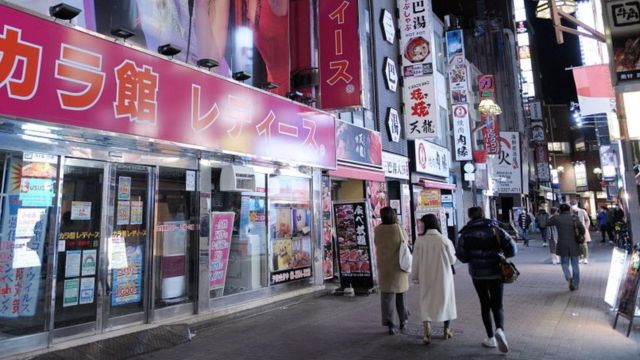 Pessoas passam pela entrada de uma loja de karaokê fechada devido à propagação do coronavírus em Tóquio