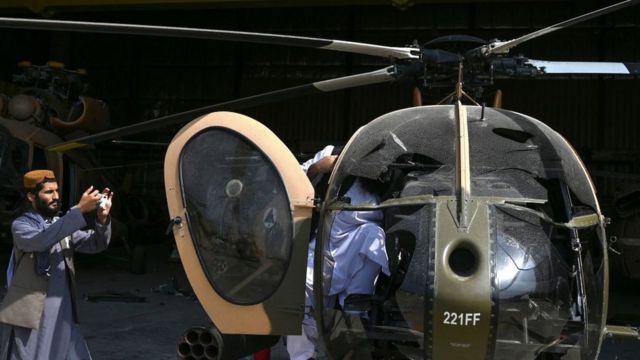 Taliban fighter taking pictures of an MD-530 helicopter in Kabul