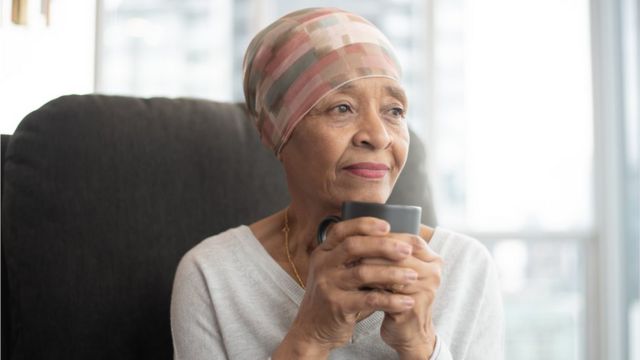 And elderly black woman sips coffee