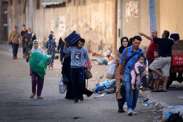 Palestinos e suas famílias caminham pelas ruas de Gaza