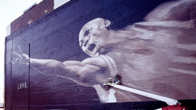 Homem finalizando pintura de grafite gigante de Michael Jordan