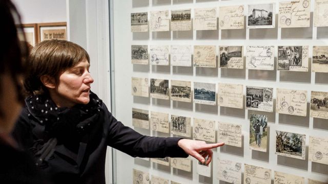 Mujer mirando una exhibición de postales de la época de la ocupación alemana en Namibia