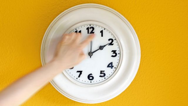Mão de pessoa ajusta ponteiro em relógio