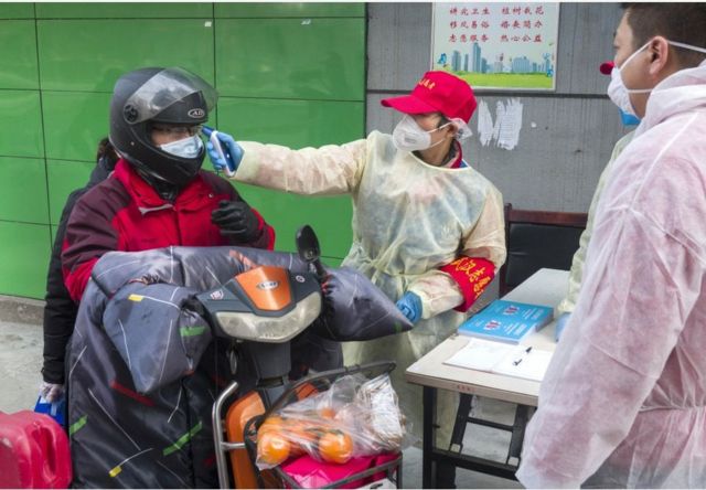 武汉市社区工作人员为进小区者量体温