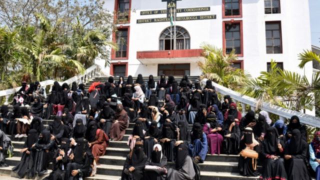 Female students wearing hijabs sitting on steps in protest against a school ban on wearing hijabs