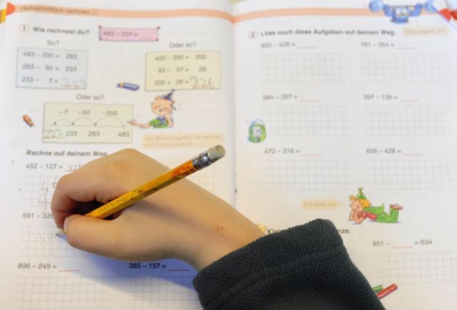 Un niño escribe en un cuaderno de ejercicios de matemáticas.