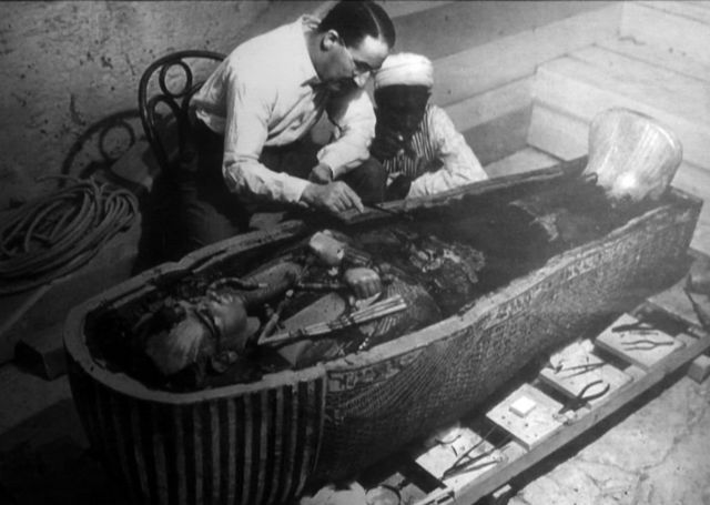 Черно-белая фотография, двое мужчин у открытого саркофага
