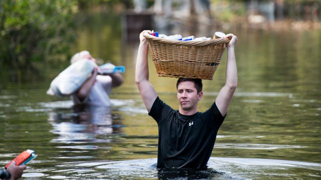 Hombre caminando en el agua en Southport, Carolina del Norte, con una cesto en la cabeza