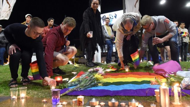 シドニーの追悼集会では虹色の旗に花やろうそくが手向けられた（13日）