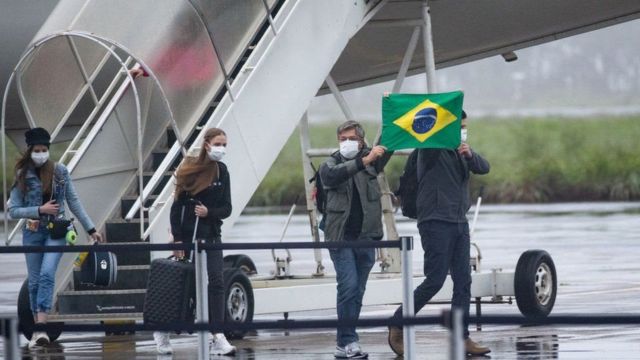 Brasileiros descem de avião usando máscaras