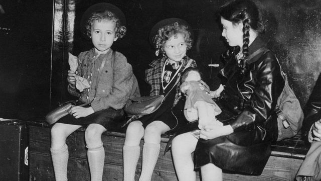 Foto em preto e branco de três meninas sentadas em um banco