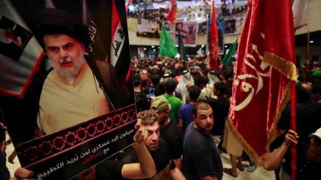 Simpatizantes al Sadr sostienen carteles con su rostro en Bagdad.