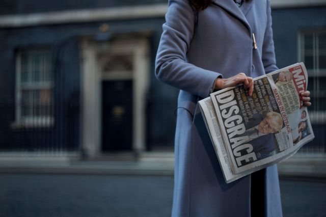 Woman with the newspaper in her hand.
