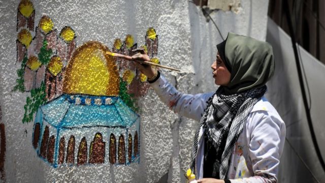 الفنانة الفلسطينية عطاف النجيلي ترسم قبة الصخرة على جدار مبنى مدمر في مدينة غزة، 24 مايو/أيار 2021