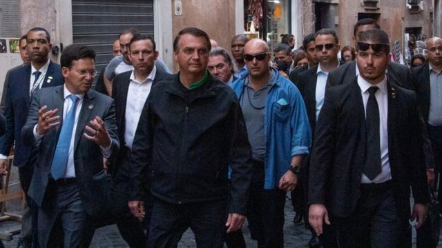Bolsonaro caminha na rua rodeado de assessores e seguranças