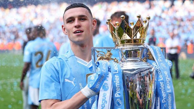 Phil Foden of Manchester City Wirth the Premier League trophy during the Premier League match between Manchester City and West Ham United at Etihad Stadium on May 19, 2024