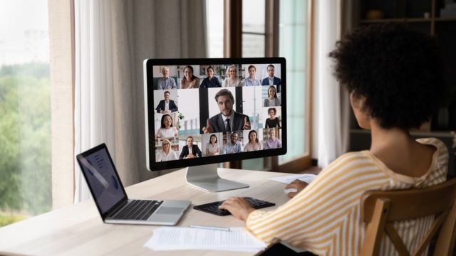 Mulher observa reunião por vídeo na tela de um computador